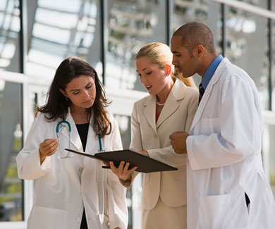 A medical team consults a folder during a stand-up meeting