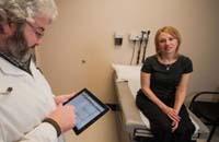 Doctor using a tablet and talking to a patient