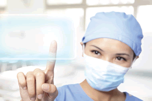 Woman dressed in scrubs touching clear screen computer with her finger.
